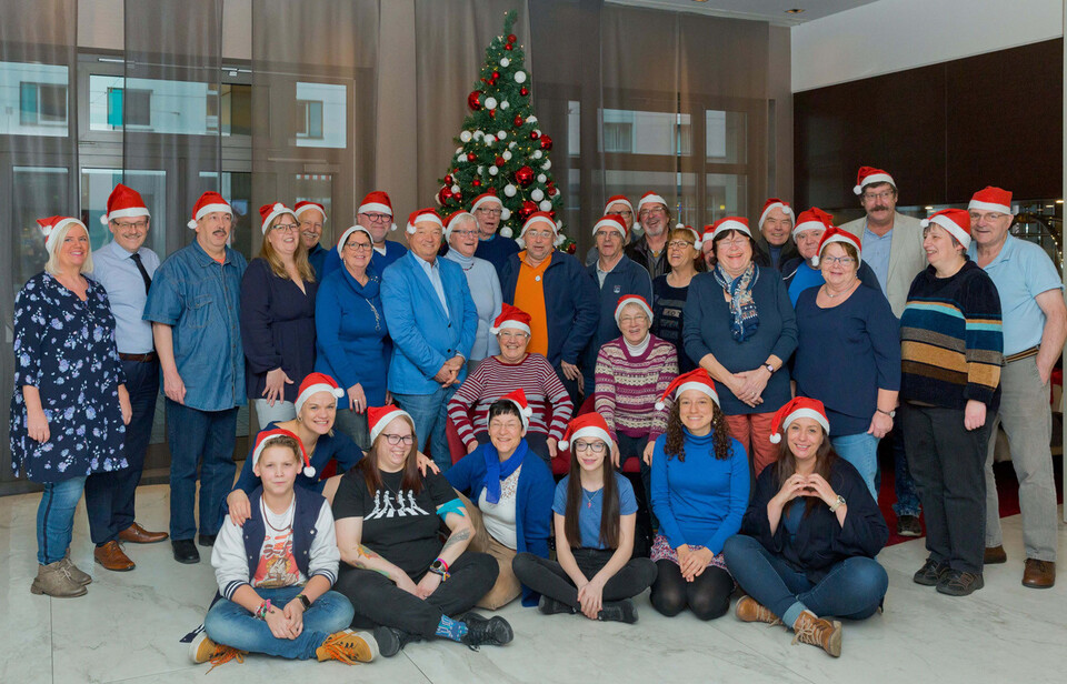 Gruppenbild aller Teilnehmer mit Weihnachtsmütze, viele haben blaue Kleidungg an.