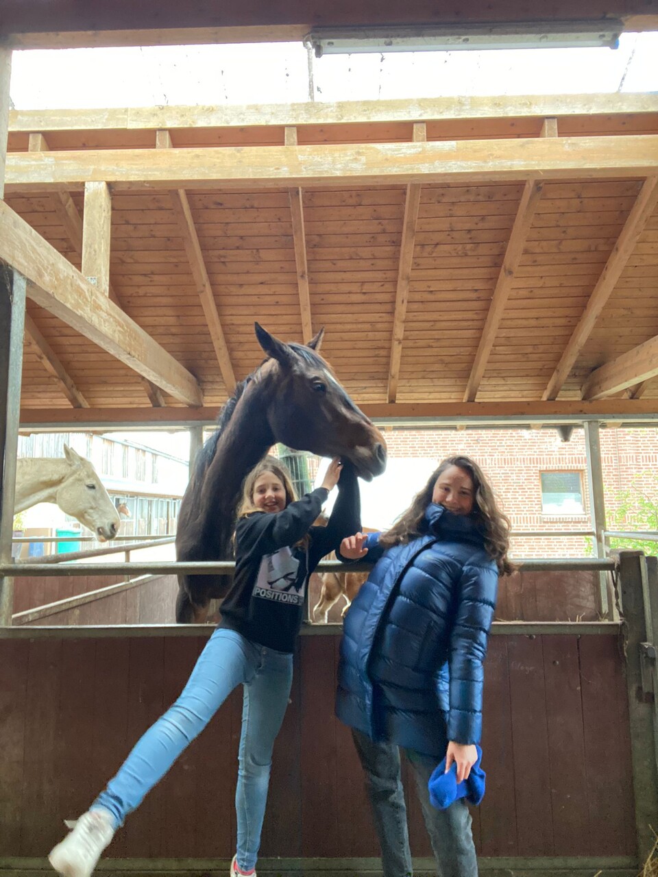 Zwei Mädchen mit Pferd in einer Reiterhalle