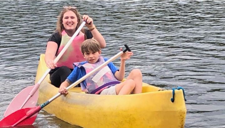 Junge Frau und Kind im Boot. Sie paddeln.